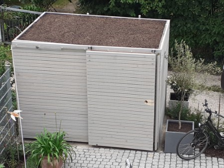 Holzverschlag mit Rhombus aus sib. Lärche in Ständerbauweise mit Dachbegrünung und Schiebetoren für Fahrrad und Mülltonnen
