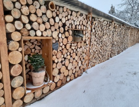 Holzverschlag als natürlicher Sichtschutz mit Dach und kleinen Fenstern